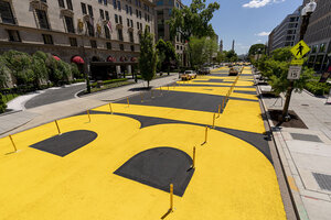A street-level view of a plaza in Washington, D.C., in 2021 with large yellow letters that spell Black Lives Matter