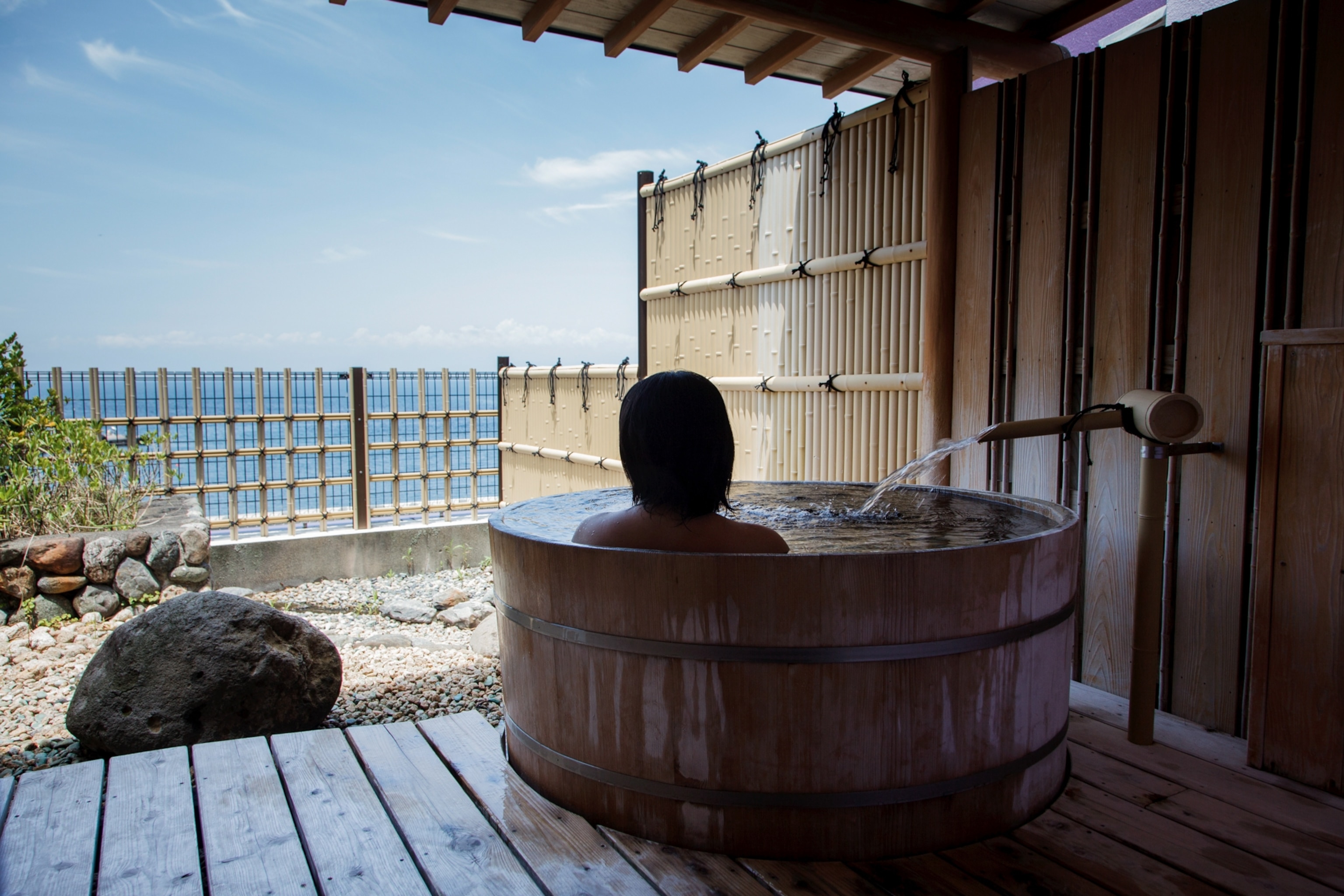 A woman in a bath looks out at the sky.