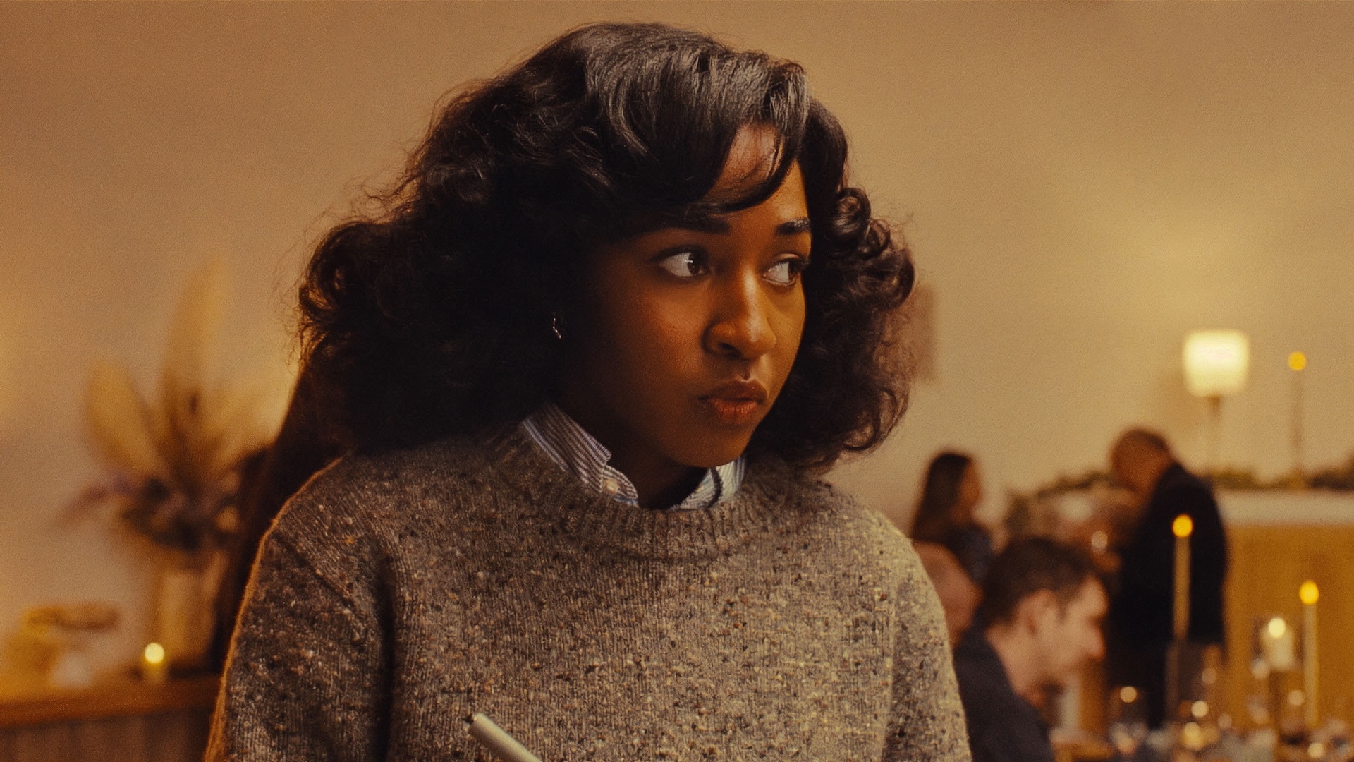 Ayo Edebiri writes down notes and stares in Opus.