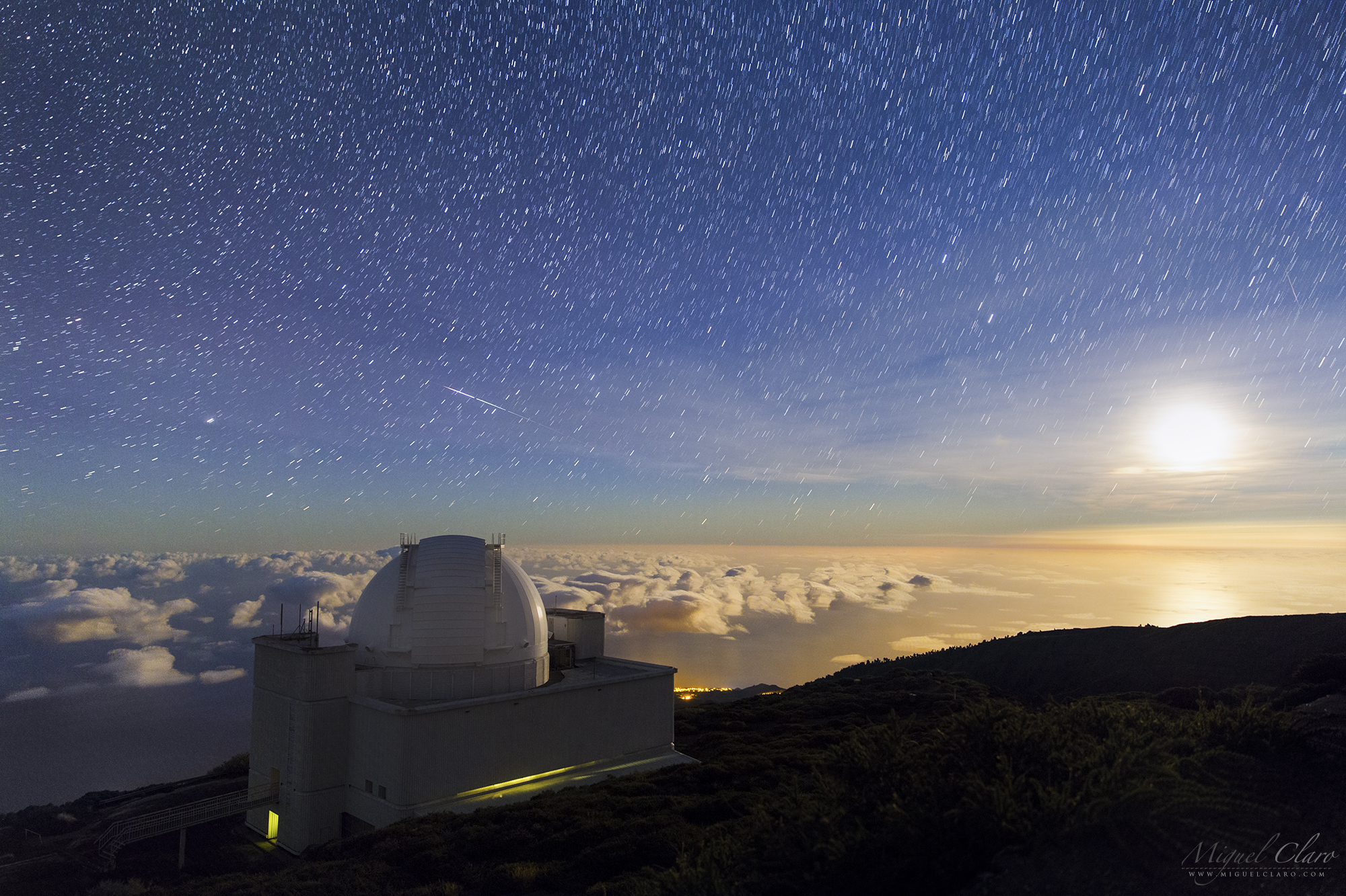An Iridium flare shines above the white dome of the Isaac Newton Telescope in this photo by astrophotographer Miguel Claro.