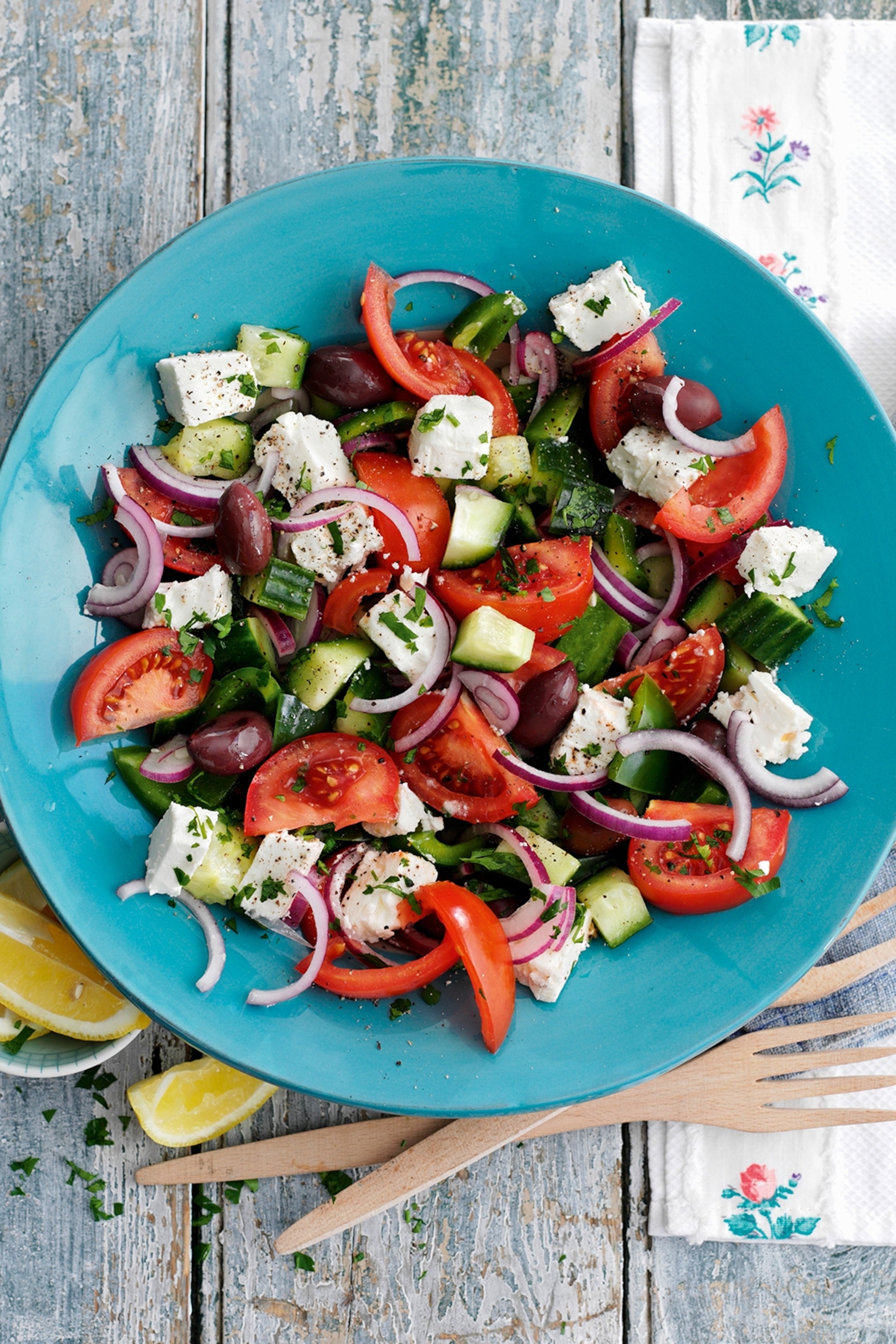 A plate of Greek salad containing tomato, cucumber, feta, kalamata olive and red onion.