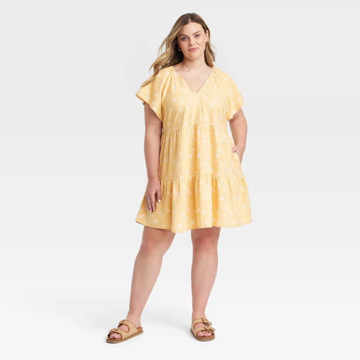 Person wearing a casual, short-sleeve, knee-length dress with a V-neck, paired with sandals. Ideal for summer shopping fashion