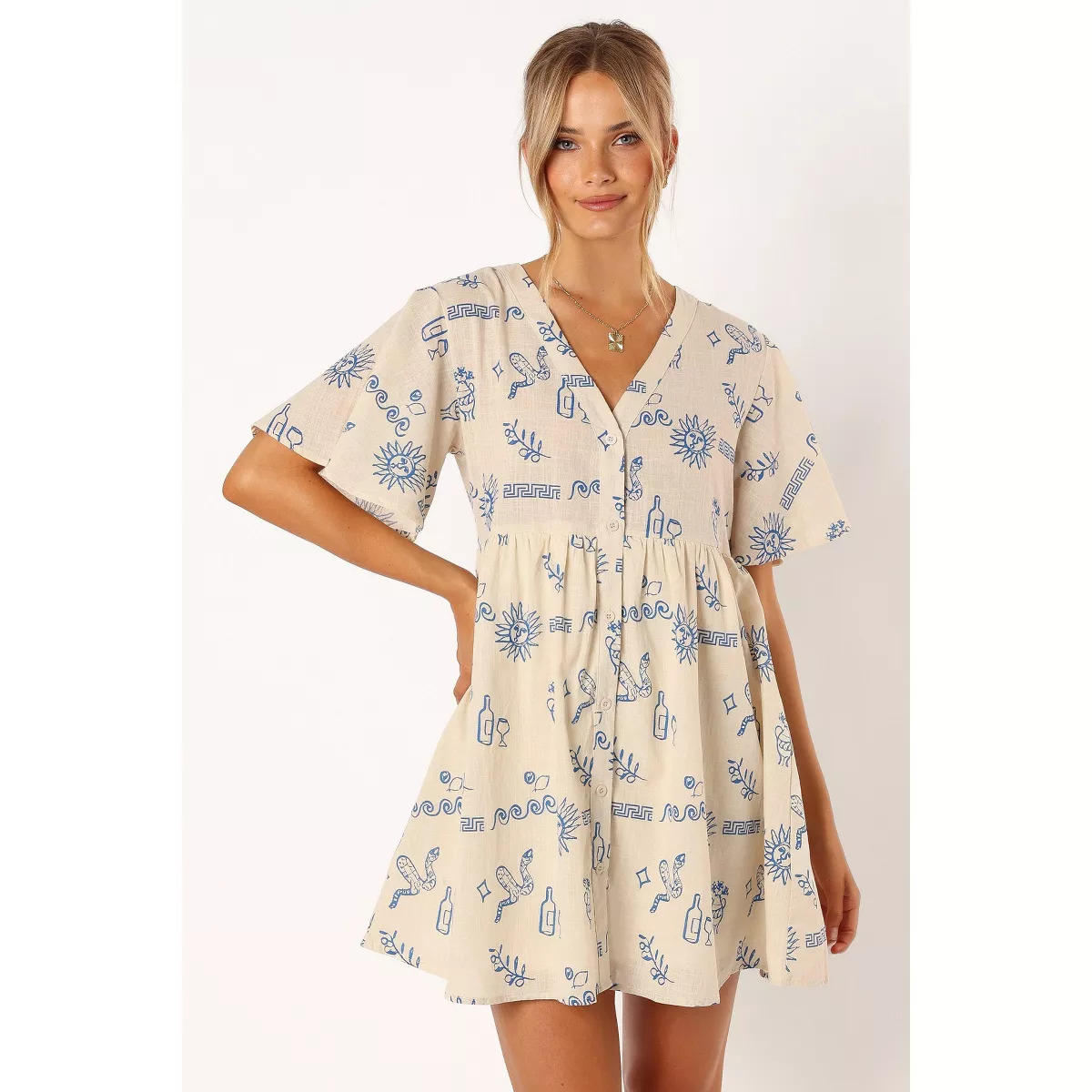 Person wearing a short-sleeved dress with blue graphic patterns and a V-neckline, posing for a fashion photo