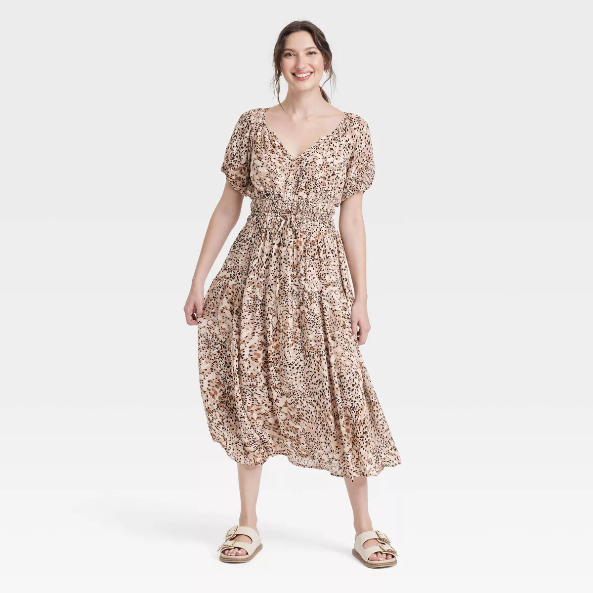 Person wearing a stylish floral dress and casual sandals, smiling