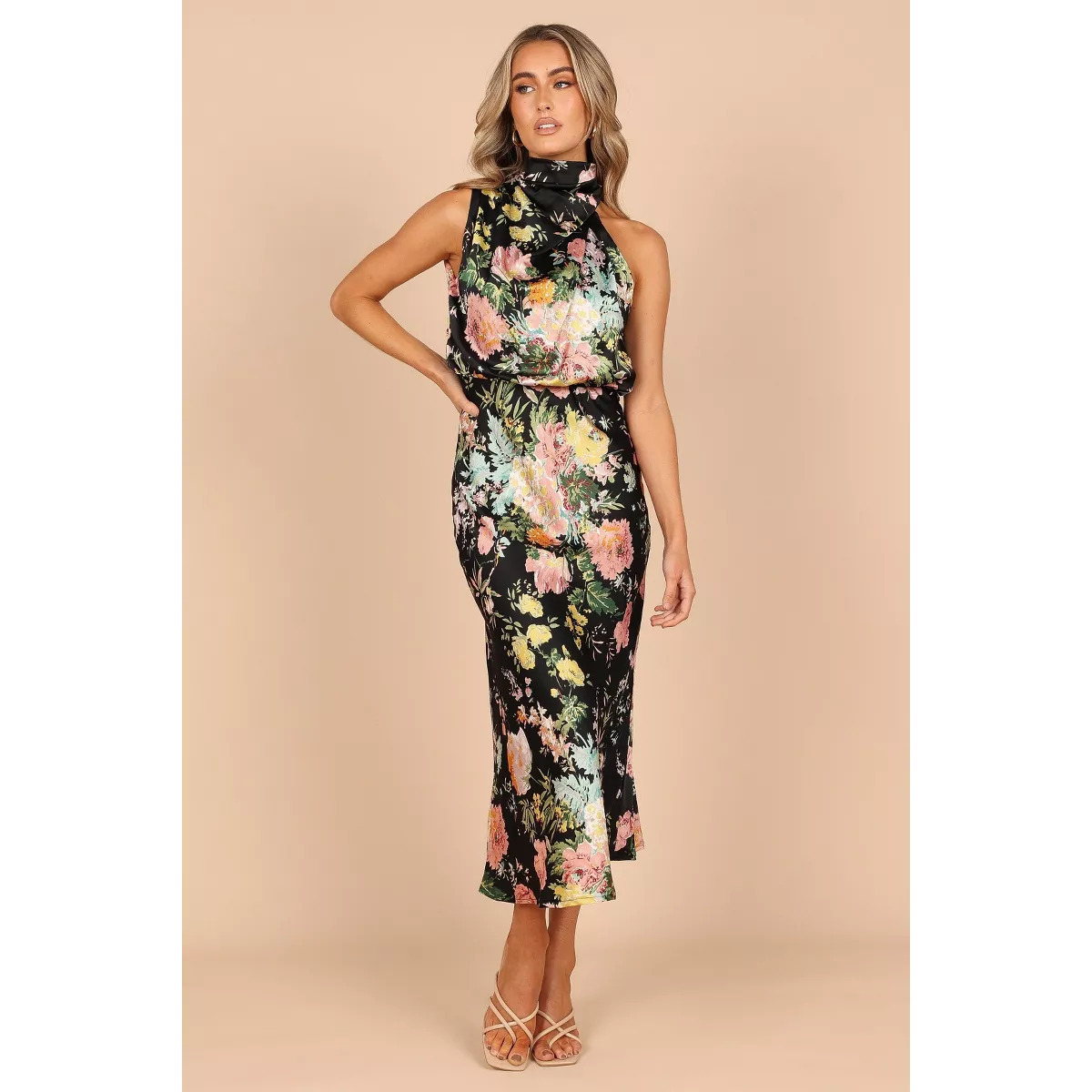 Person wearing a floral sleeveless dress with a high neckline, posing confidently. The dress has a fitted, elegant style suitable for events