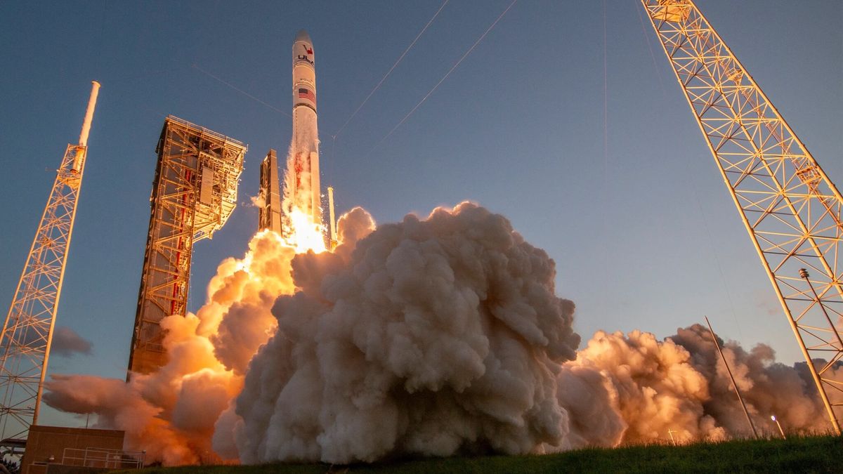 ground-level view of a large white rocket launching into a clear sky
