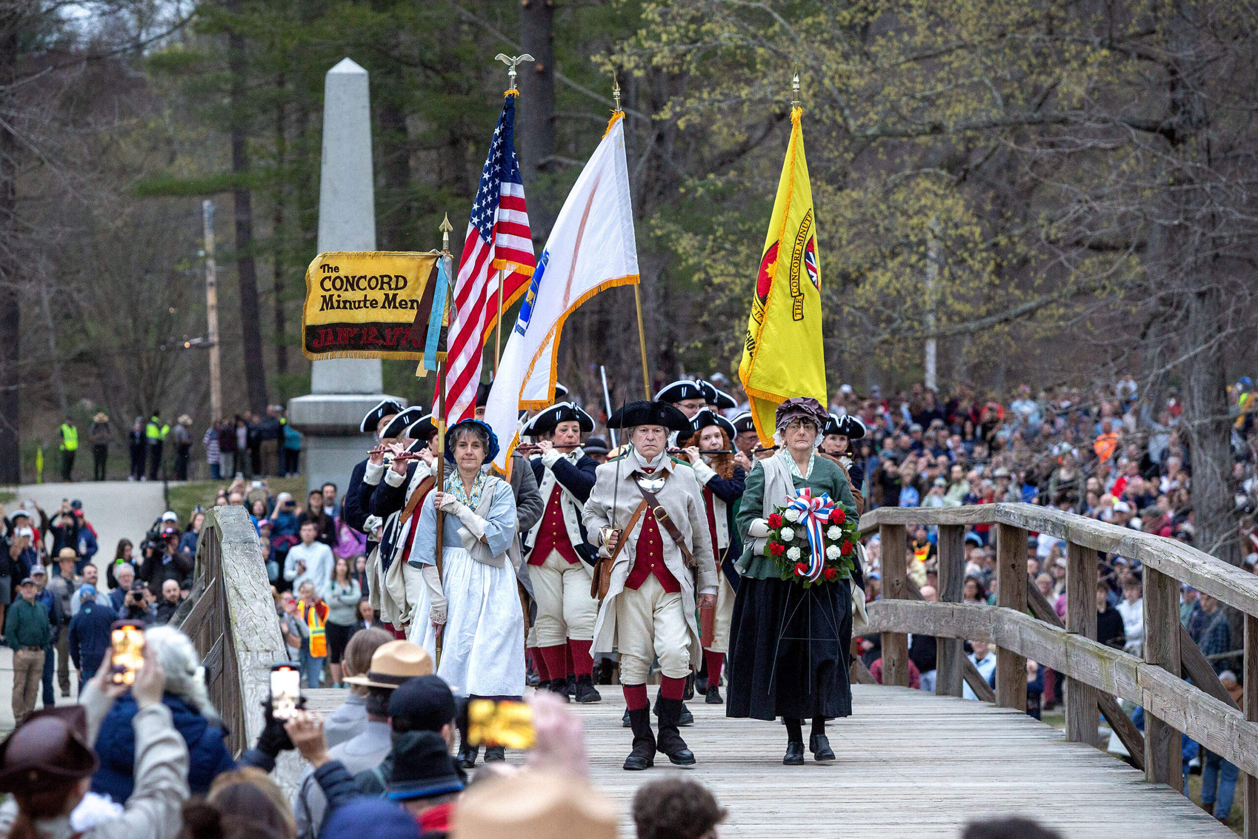 The Concord Minutemen cross the Old North Bridge at the start of Concord's commemoration the 250th anniversary of American Revolution. (Robin Lubbock/WBUR)