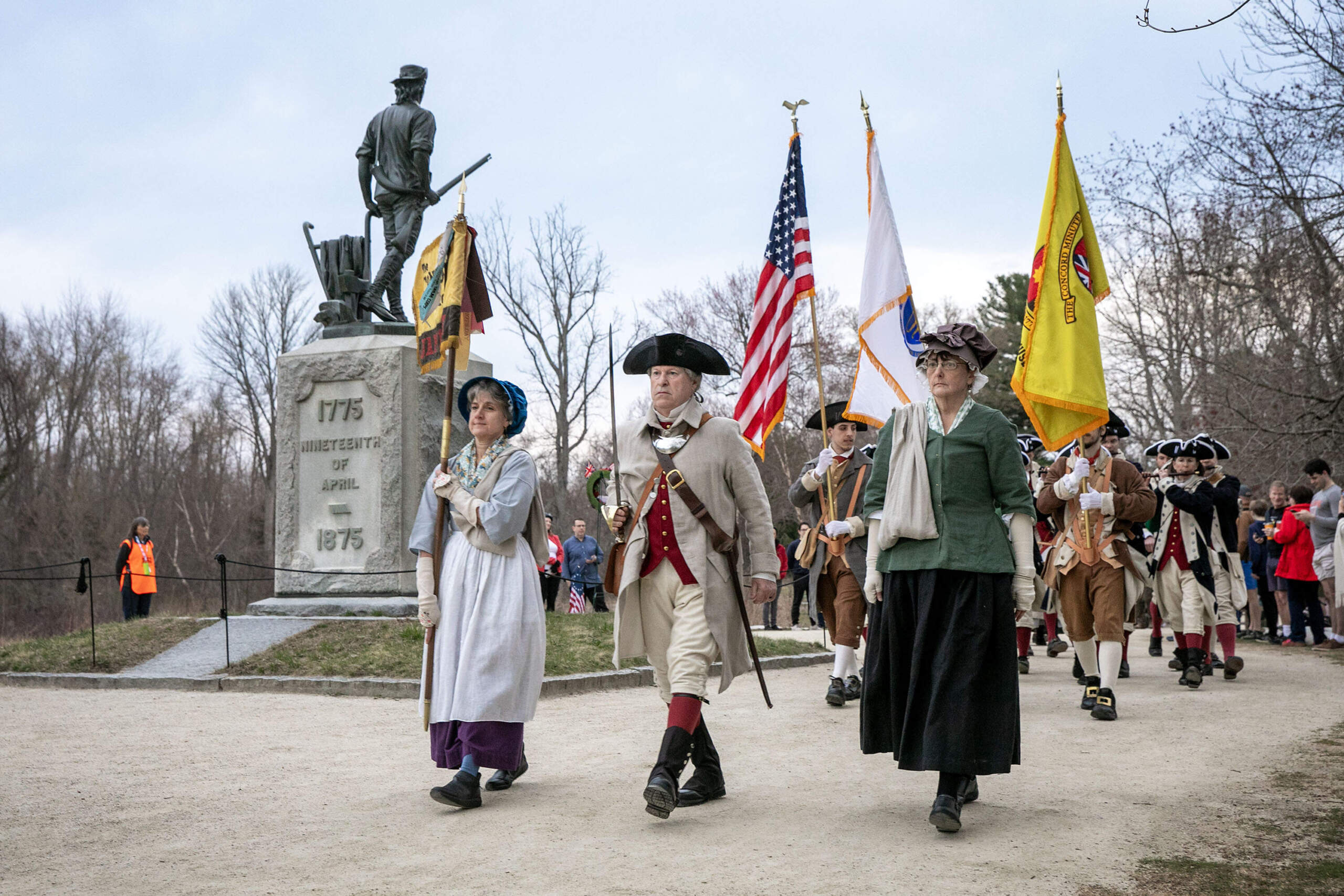 The Concord Minutemen pass the Minuteman Statue at the site of the initial confrontation in Concord between the Minutemen and the British on April 19th 1775. (Robin Lubbock/WBUR)