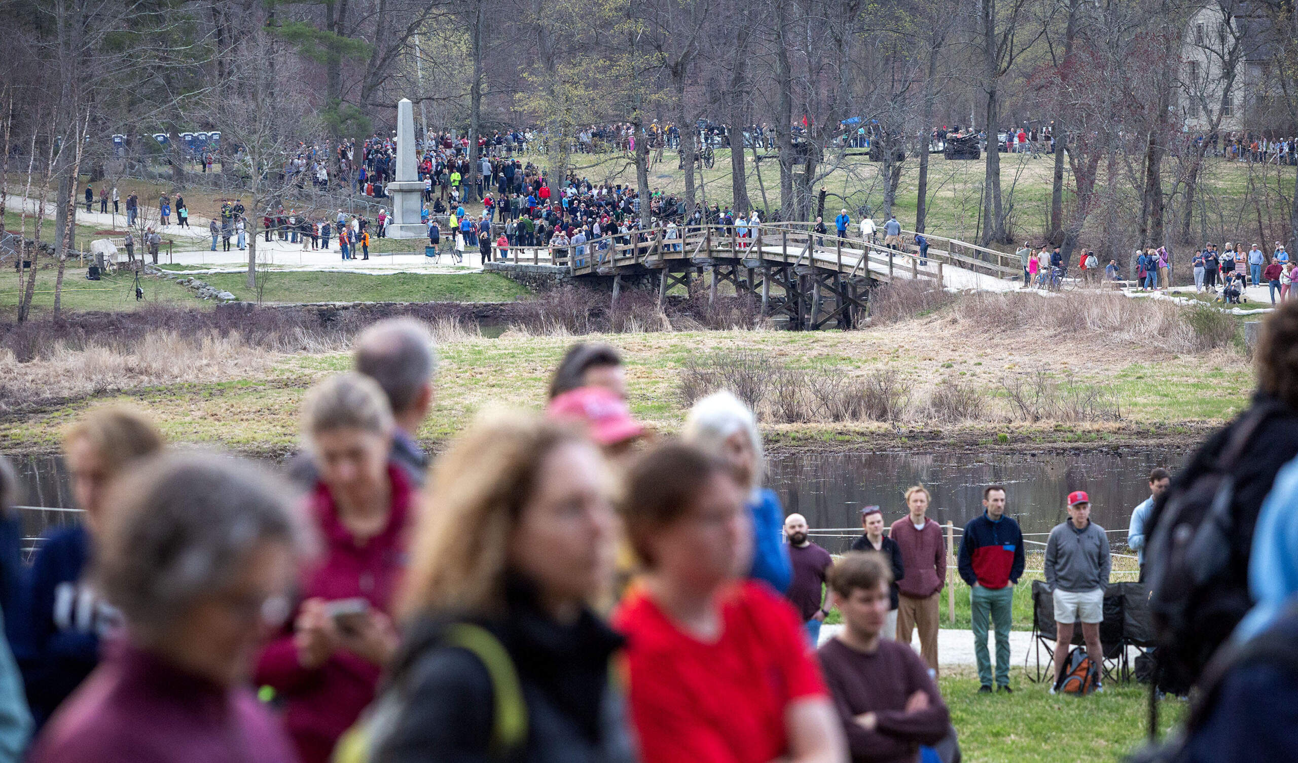 A crowd gathers at the Old North Bridge and Buttricks Hill for the commemoration the 250th anniversary of the Battle of Concord. (Robin Lubbock/WBUR)