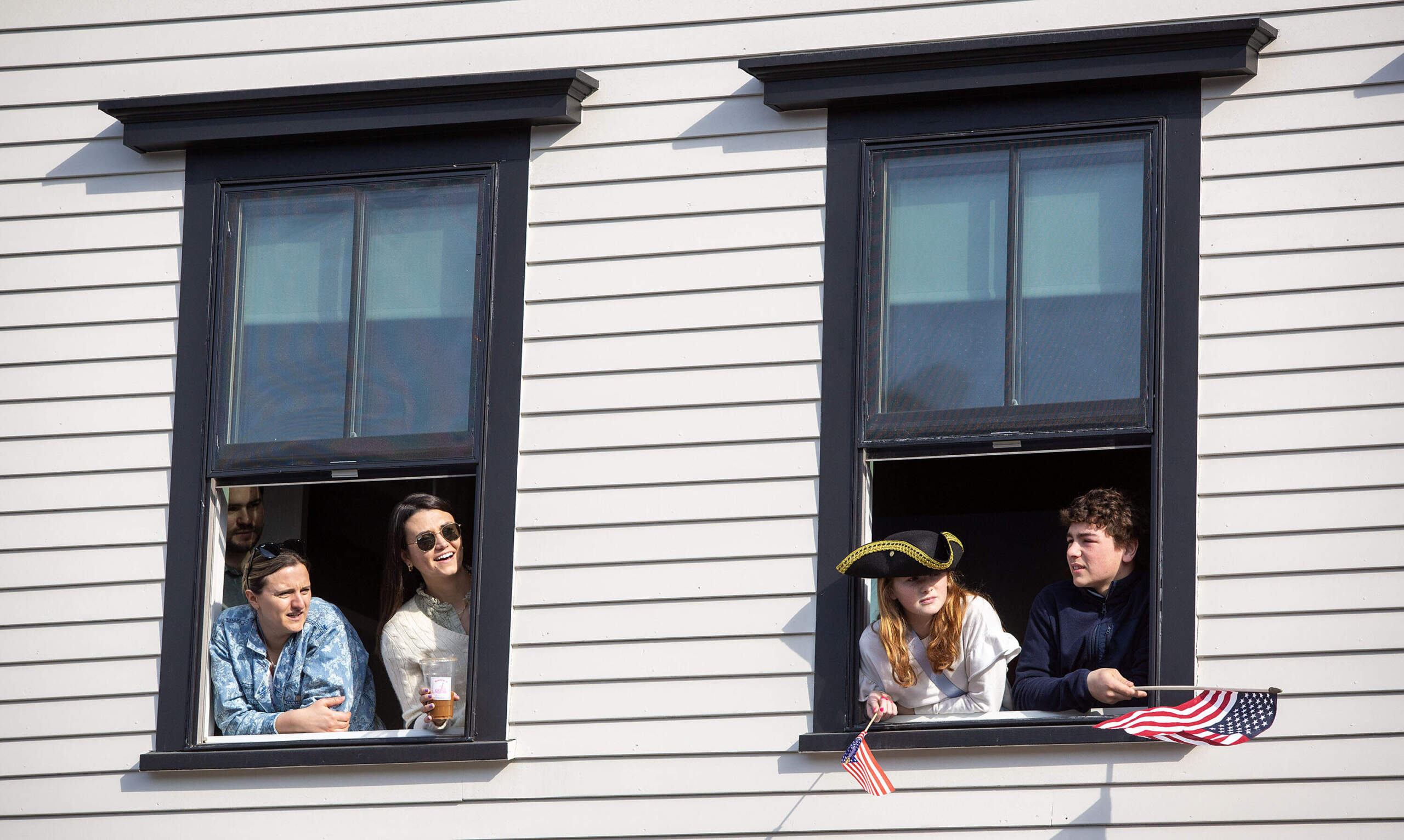 People lean out of windows on Main Street in Concord to watch the parade in commemoration of the 250th anniversary of the Battle of Concord. (Robin Lubbock/WBUR)