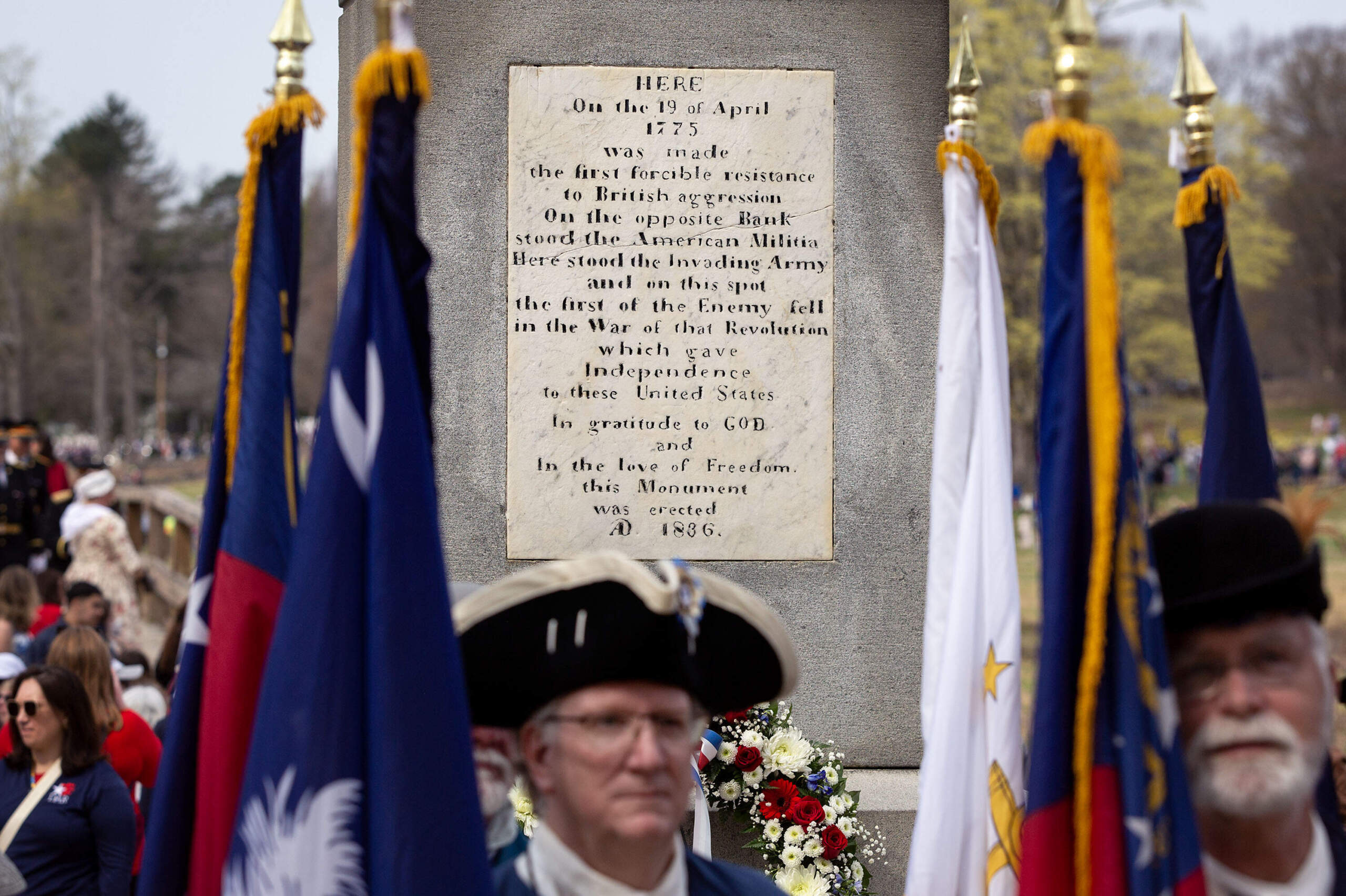 Revolutionary War reenactors stand in front of the 1836 Battle Monument by the Old North Bridge during the parade for the 250th anniversary commemoration of the Battle of Concord. (Robin Lubbock/WBUR)