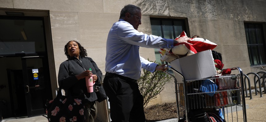 Fired employees of the Health and Human Services Department take personal belongings with them as they leave the Mary E. Switzer Memorial Building in Washington, D.C. on April 1, 2025. Widespread layoffs began Tuesday across HHS offices.
