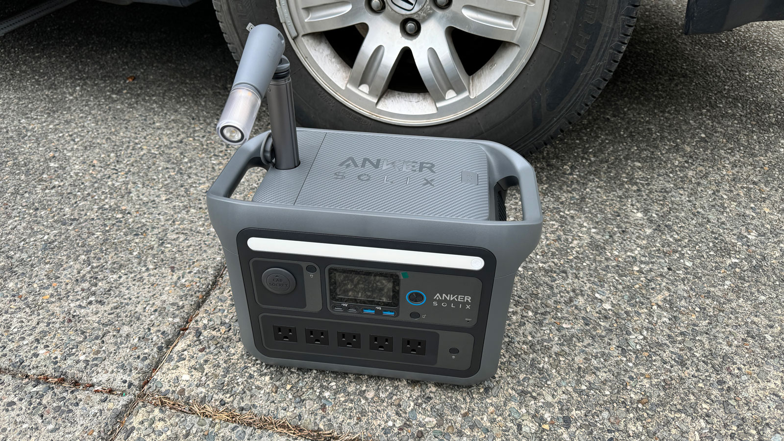  Anker portable power station sitting in front of a car wheel