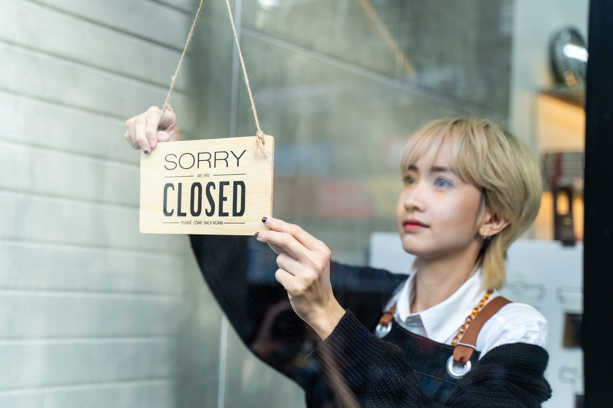 Asian hairdresser turns Welcome we are open sign on glass door to reopen small business
