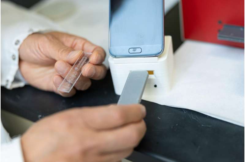 Saliva samples are inserted into a reader that transmits cortisol measurements to a smart phone. Credit: Andrew Higley UC lab-on-a-chip devices take public health into home