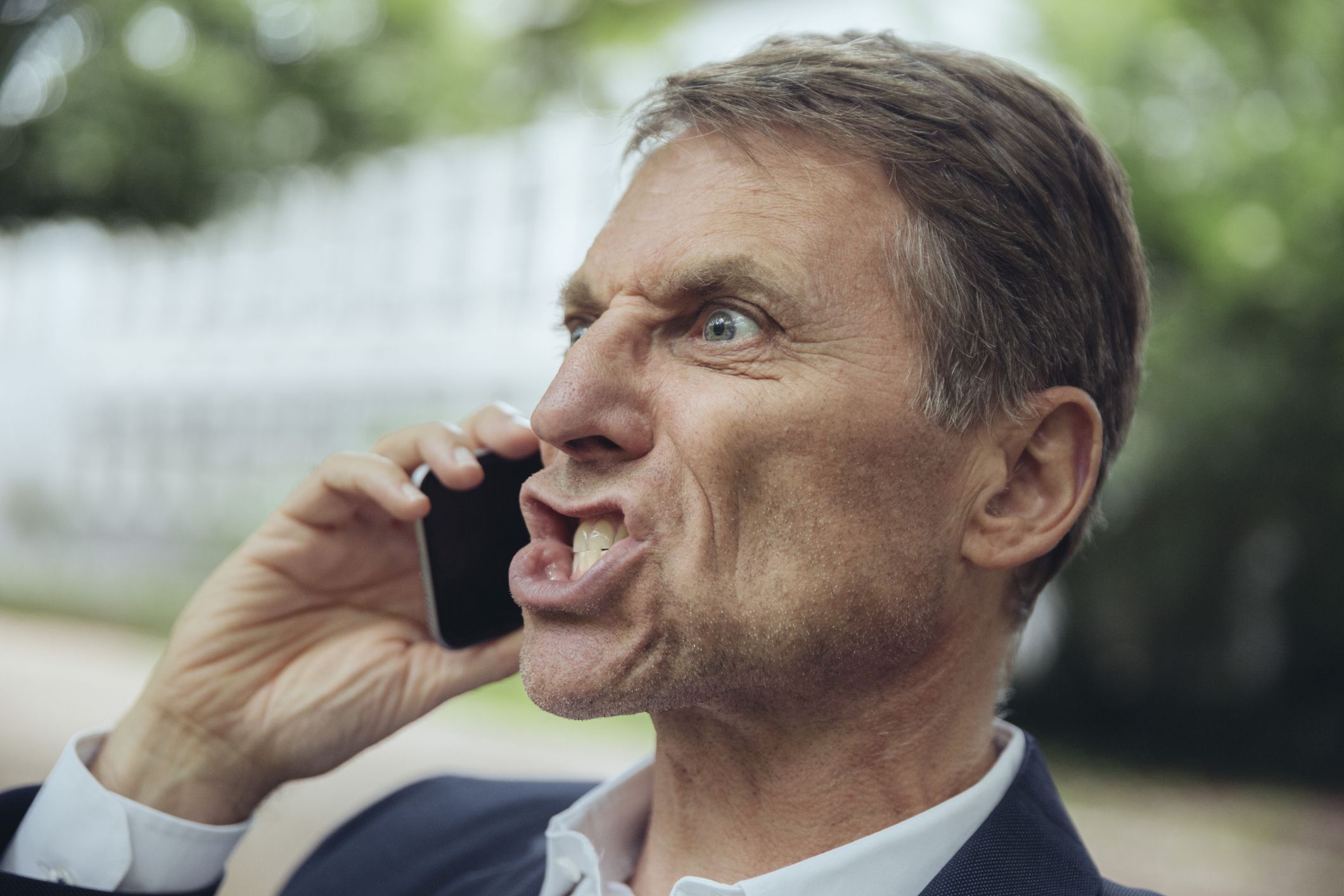 portrait of angry mature businessman outdoors on the phone