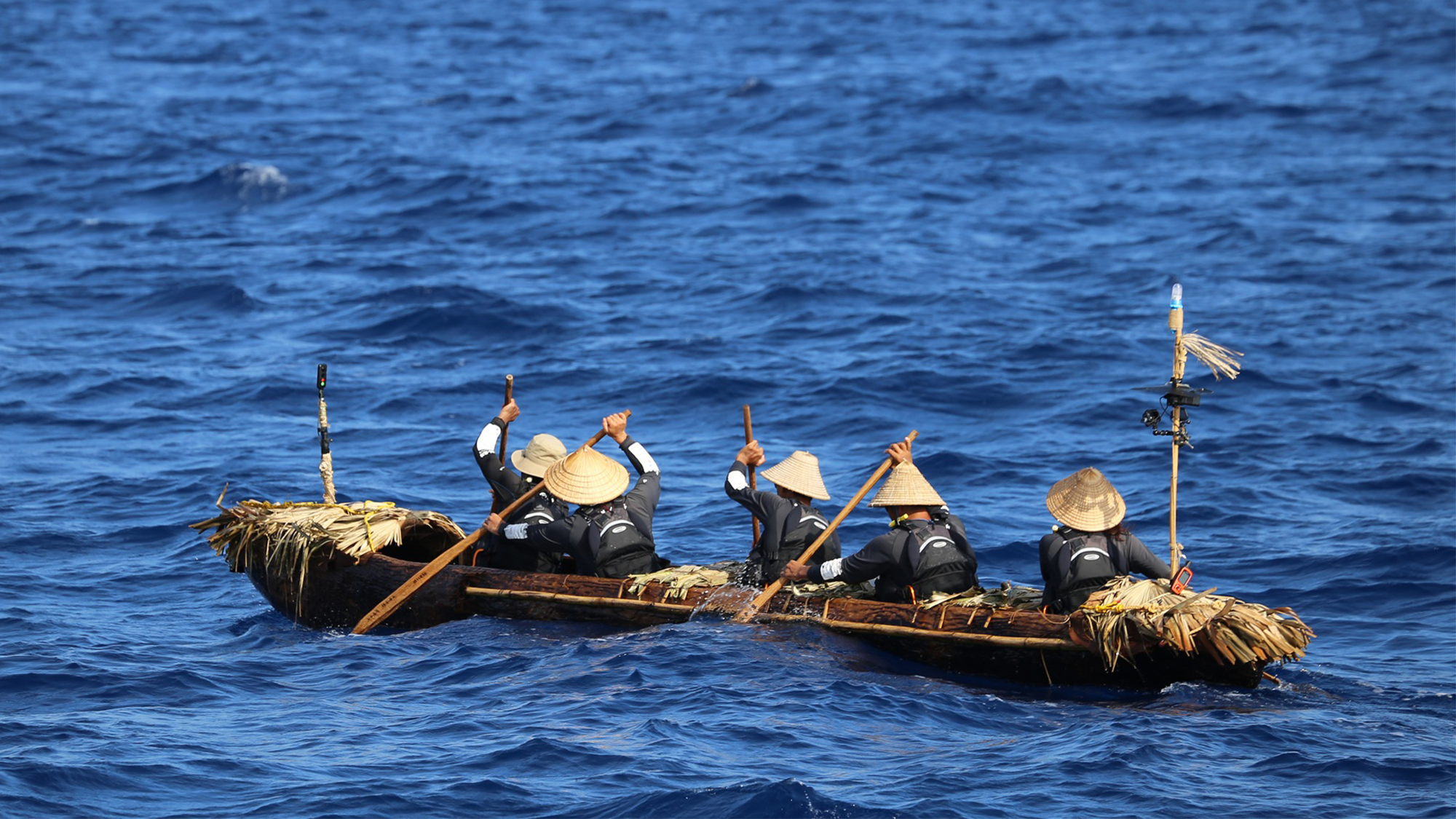 a team of five scientsts paddle a dugout canoe that is a replica of one used 30,000 years ago