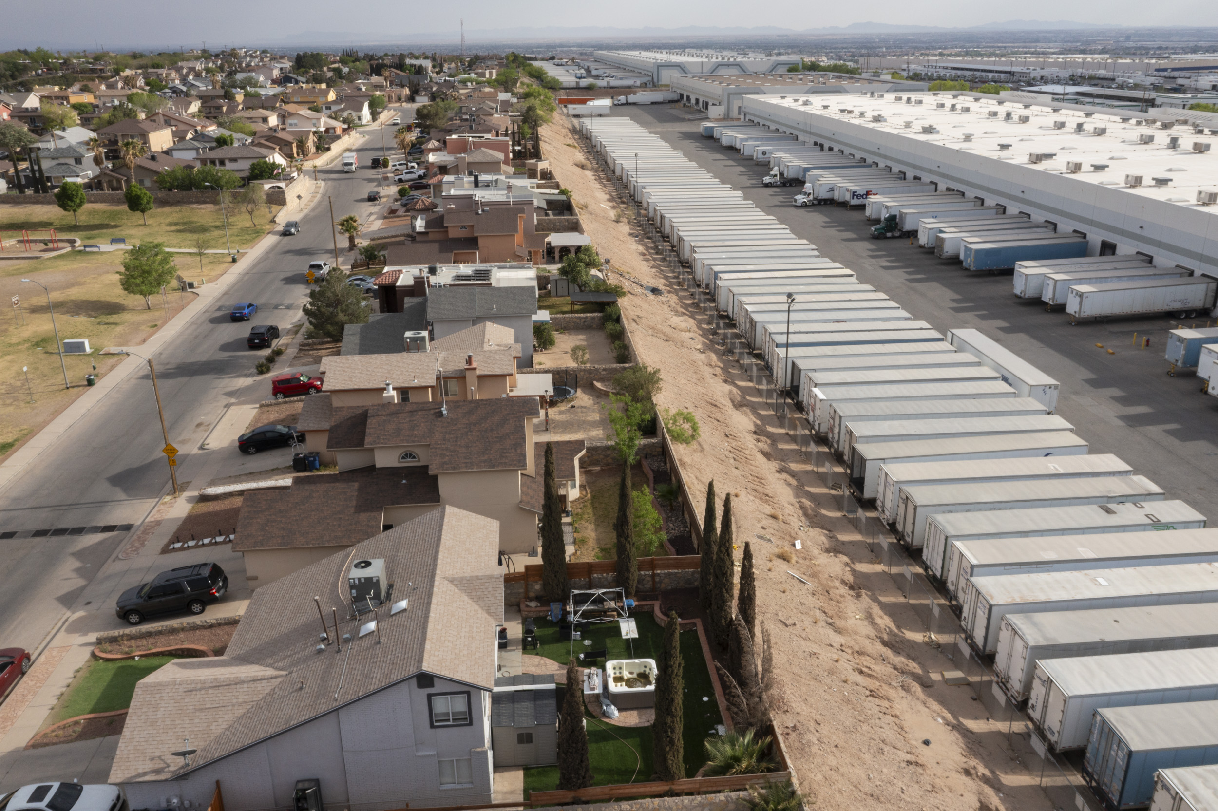 An aerial view of a neighborhood right next to a facility warehouse with lots of trucks