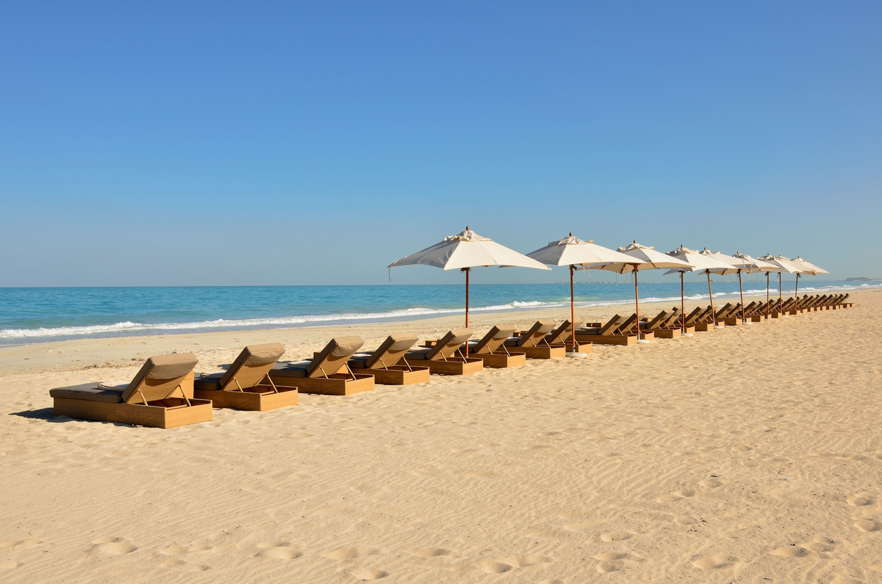 Sunbeds and sunshades on the beach of the Park Hyatt hotel on Saadiyat Island, Abu Dhabi, United Arab Emirates.