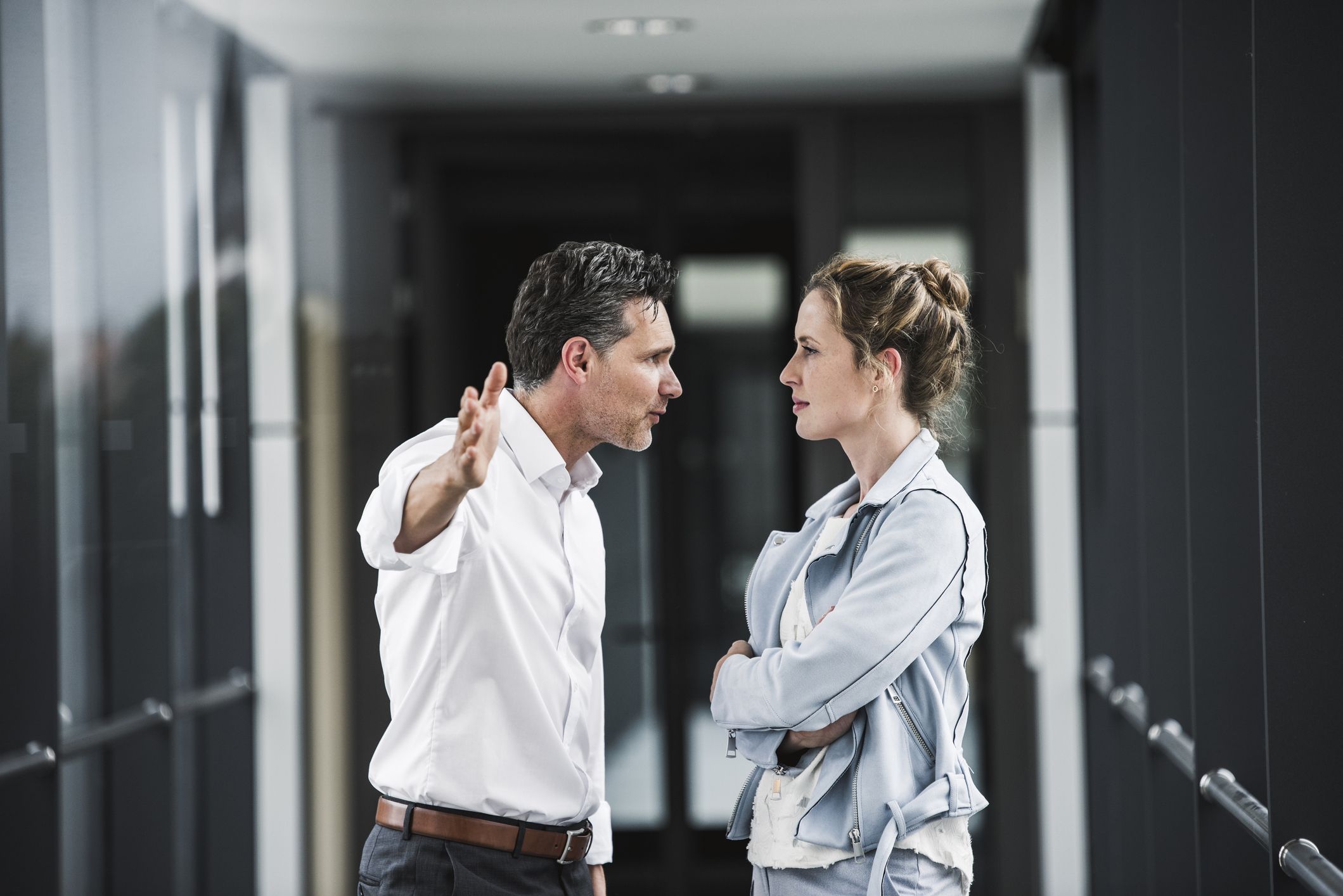 Businesswoman and businessman arguing in office passageway Businesswoman and businessman arguing in office passageway