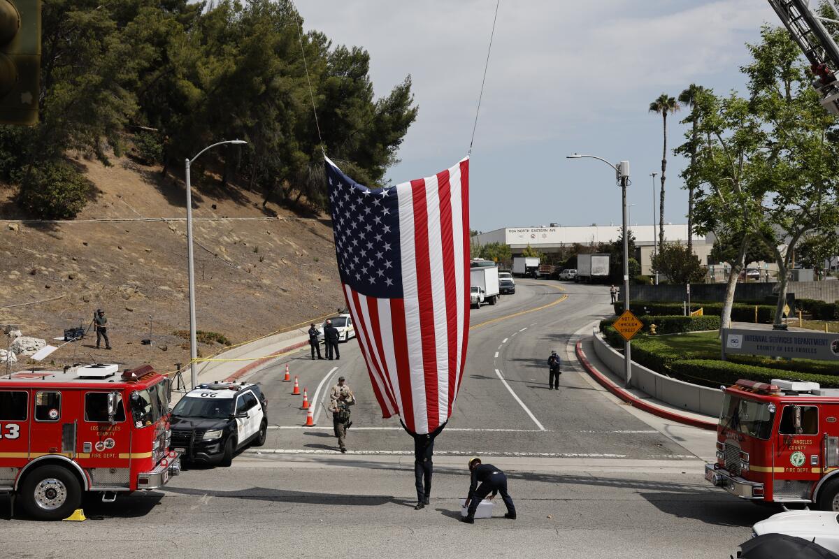 An American flag is suspended between two fire trucks.