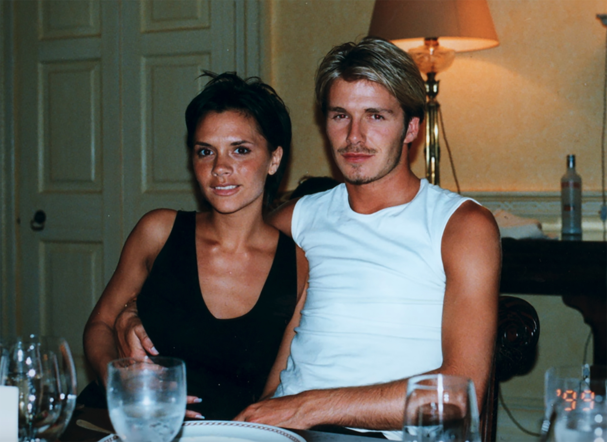 David Beckham in a white tank top, Victoria Beckham in a black top.