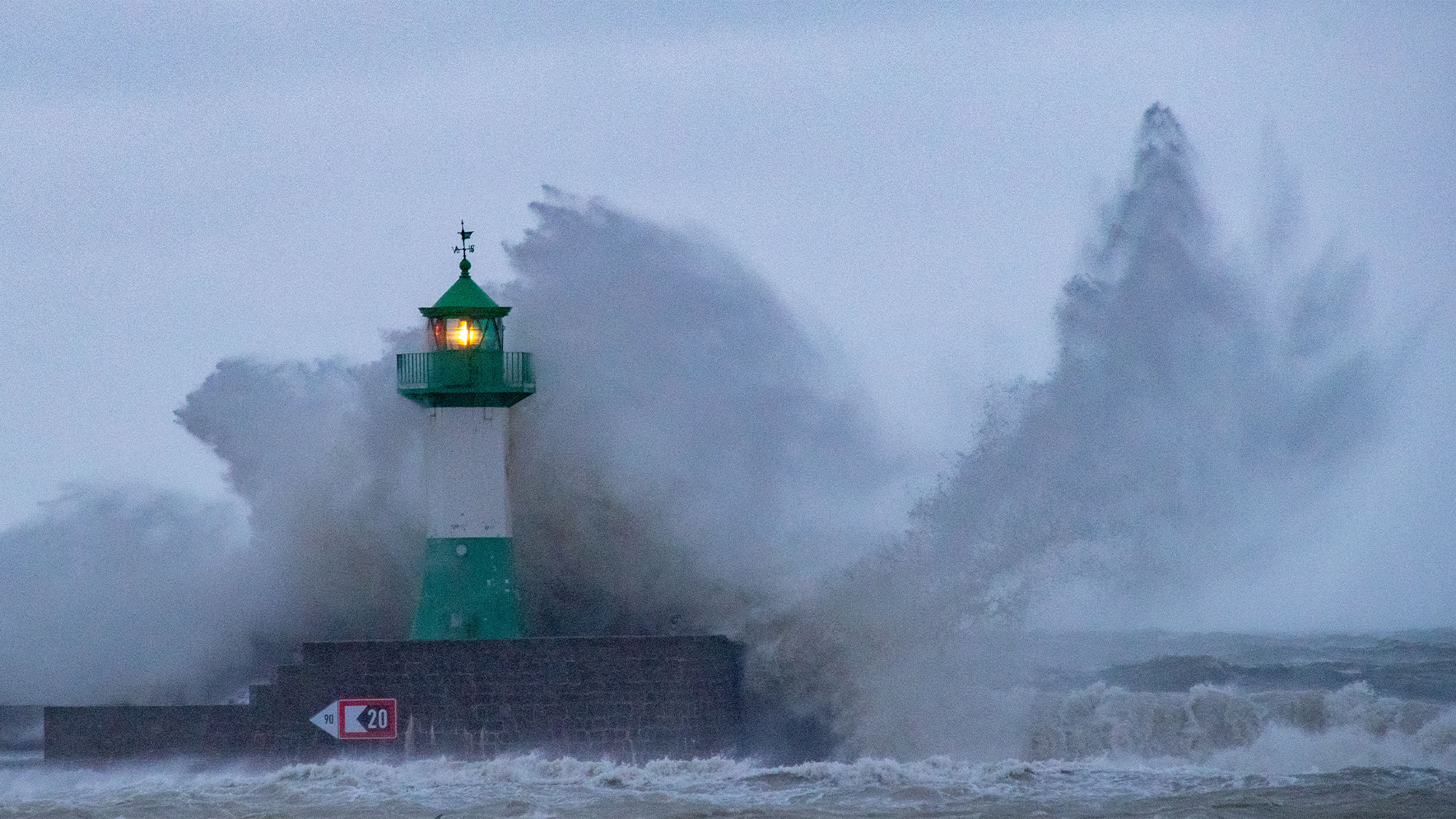 waves crash by a giant lighthouse