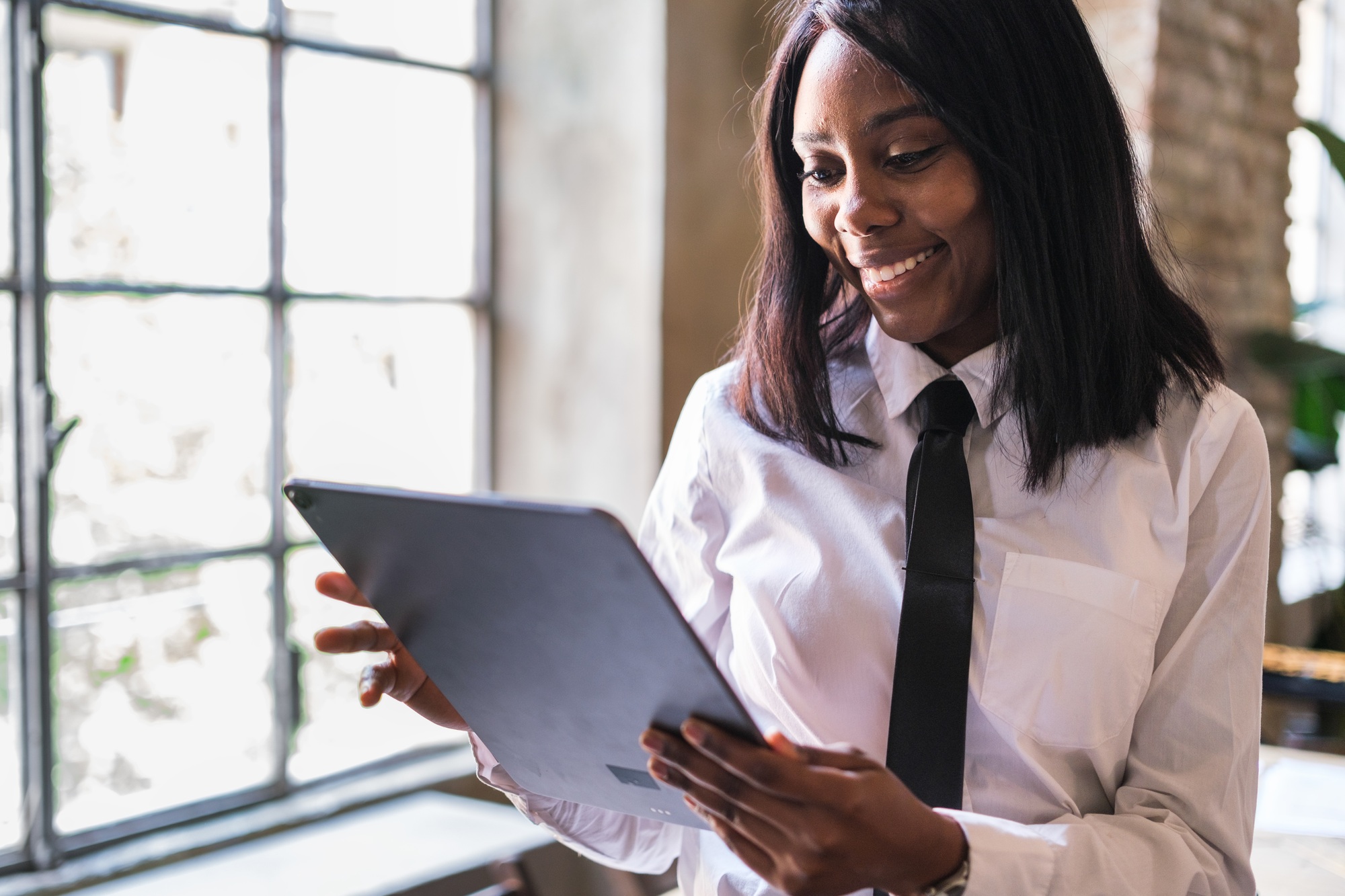 Young businesswoman in suit using tablet for her workflow in board room