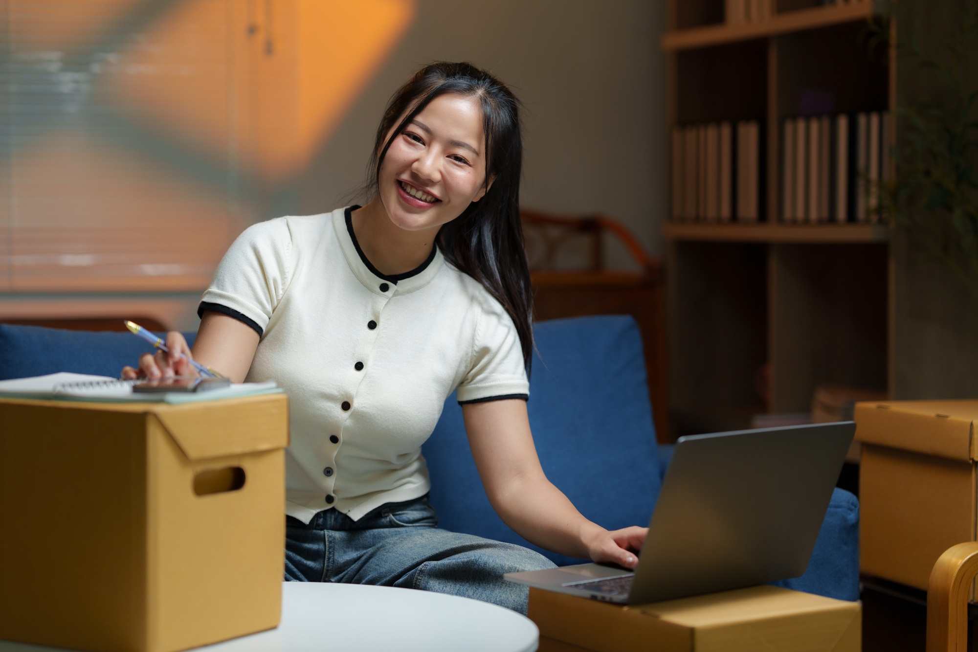 Asian woman managing inventory and logistics using laptop at home