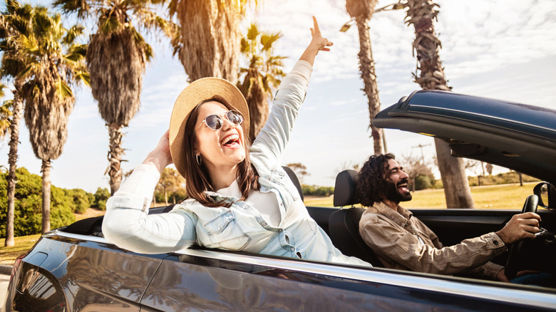 a couple driving a convertible and enjoying themselves