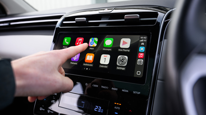 a driver touching the Maps icon through Apple CarPlay