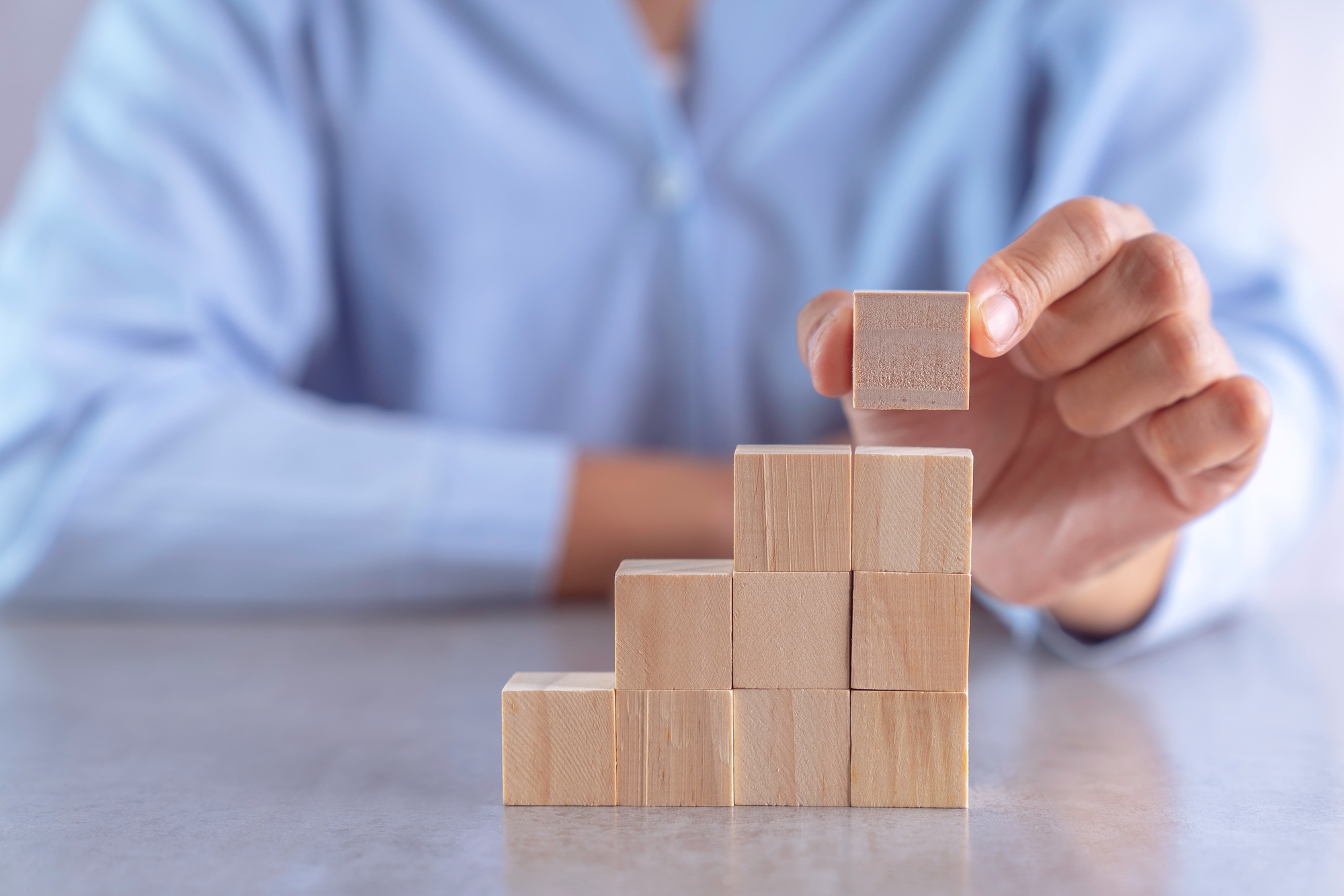 hand arranging wood cube stacking as stair step shape, mock up for create symbol or logo, business g