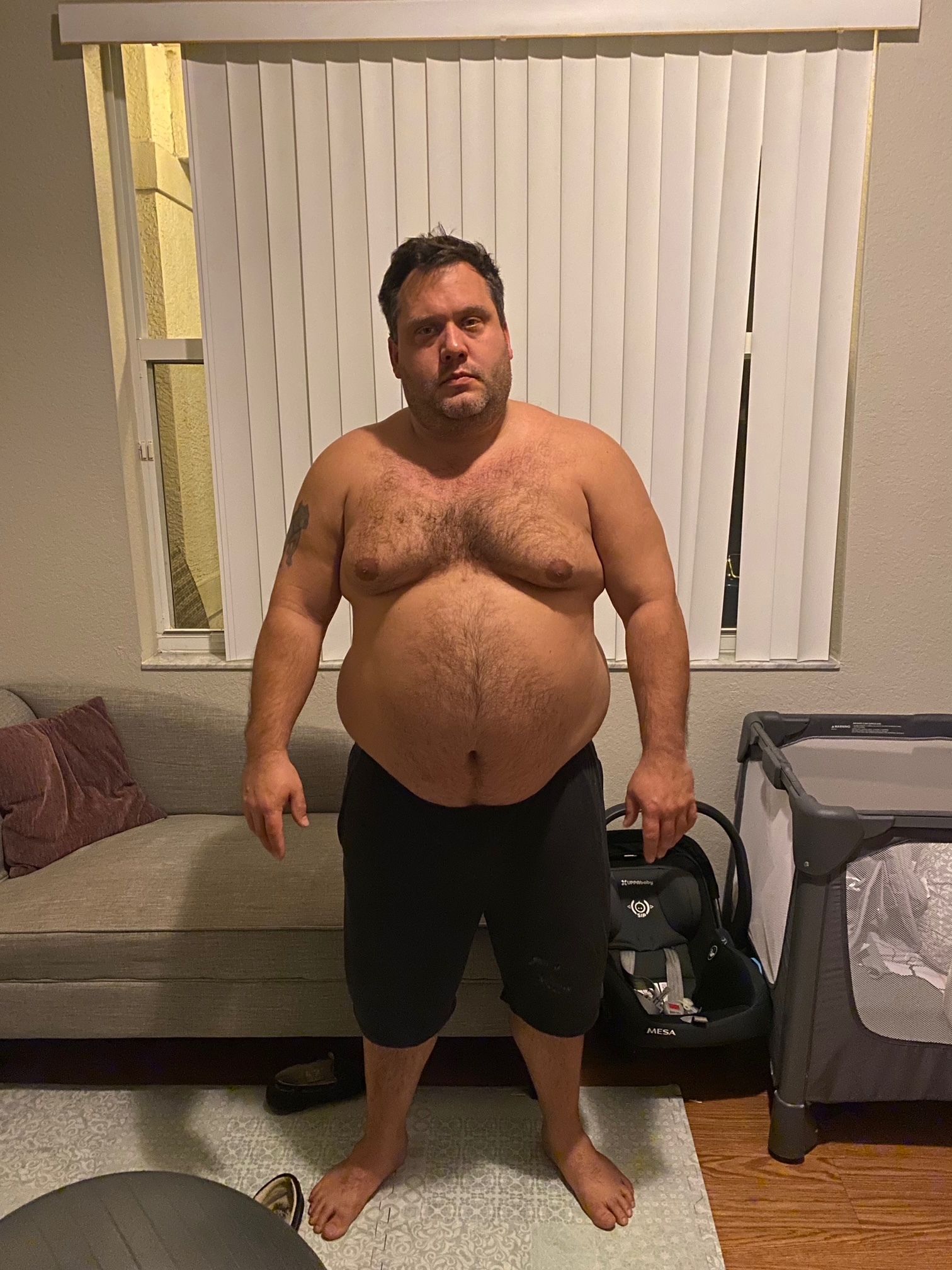 overweight james votraw standing shirtless in a room