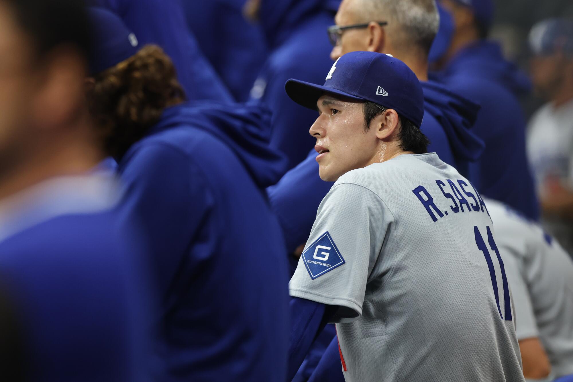 Dodgers pitcher Roki Sasaki watches from the dugout after being pulled in the ninth inning.