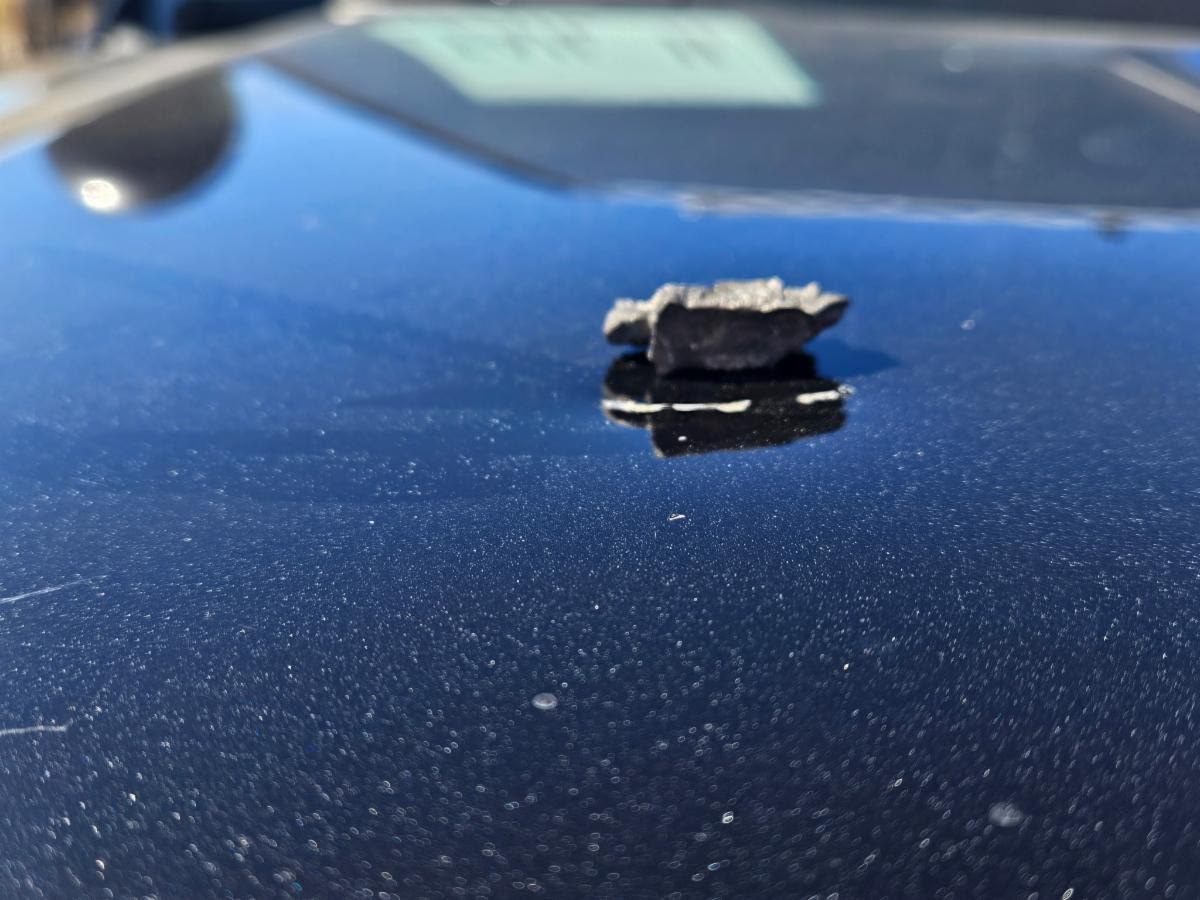 Close-up of a small chunk of shrapnel on a car hood.