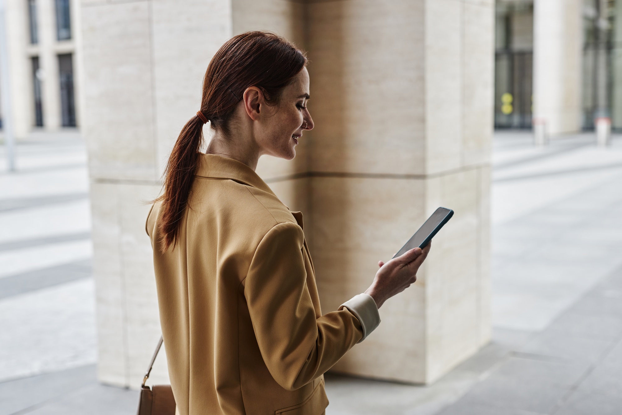 Young brunette female employee looking at smartphone screen